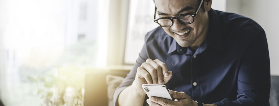 Person in glasses smiles while using their cell phone.